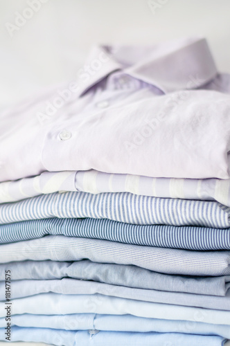 Neatly folded men's shirts of pastel tones. Close-up with soft focus