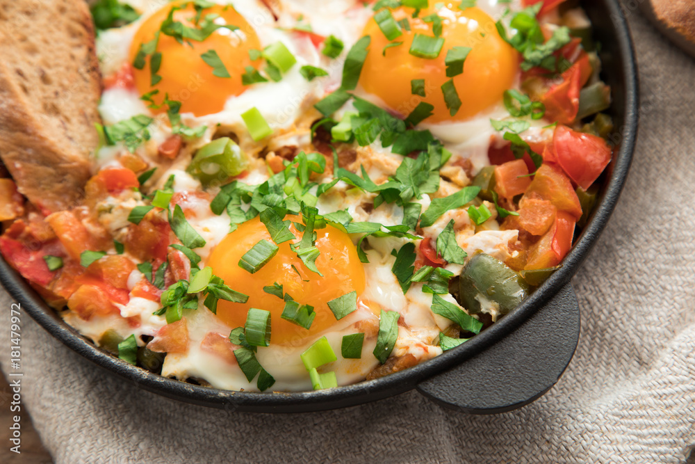 Shakshuka with eggs, tomato, and parsley in a iron pan. Shakshuka - traditional israeli tomato stew with eggs Shakshuka with eggs, tomato, and parsley in a iron pan. Shakshuka - traditional israeli tomato stew with eggs