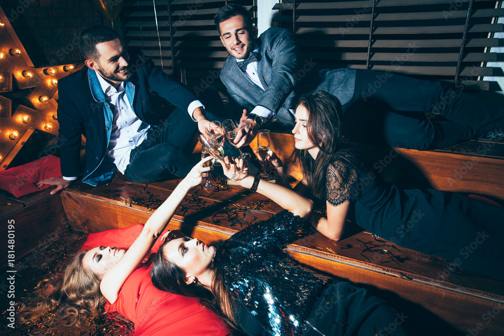 Φωτογραφία Group of friends at club lying on the floor and cheers after party having fun