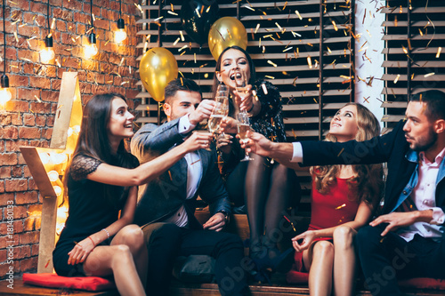 Cheers! Group of friends clinking glasses of champagne during party celebrating