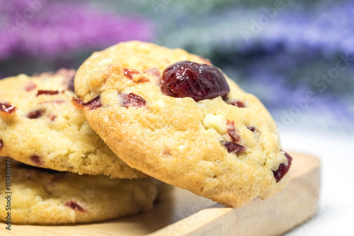 Cranberry cookies on wooden plate with blurred pink and violet flowers background