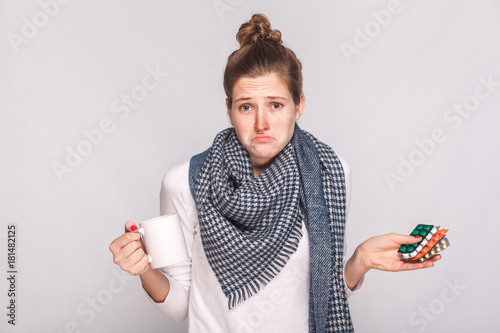 Fotografie Worry puzzled woman holding cup with tea, many pills