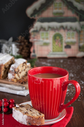 Sliced Christmas Stollen. Traditional german christmas cake with dried fruits and icing            with red coffee mug 