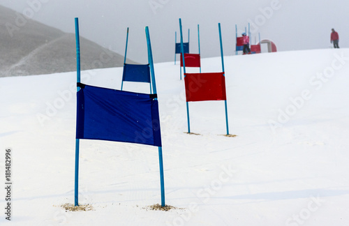 Фотография Children skiing slalom racing track with blue and red gates.