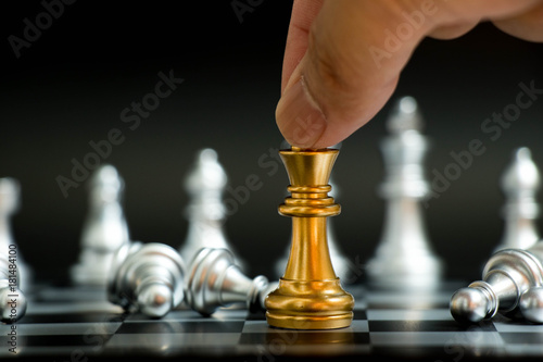 Businessman hold gold king with silver pawn lay down in chess game on black background (Concept for vitory in business, leadership)