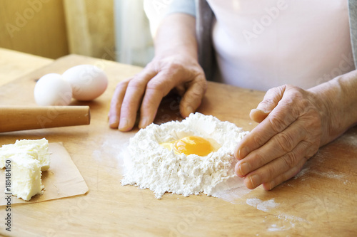 Elderly woman cooks french croissants, bare wrinkled hands, ingredients, soft warm morning light,top view