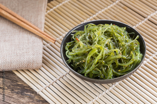 wakame seaweed salad in a ceramic dish on bamboo mat. popular and delicious japanese food appetizer. photo