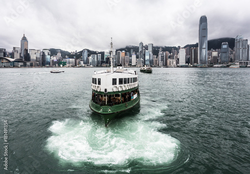 Star ferry on a cloudy sky with the famous skyline in Hong Kong.