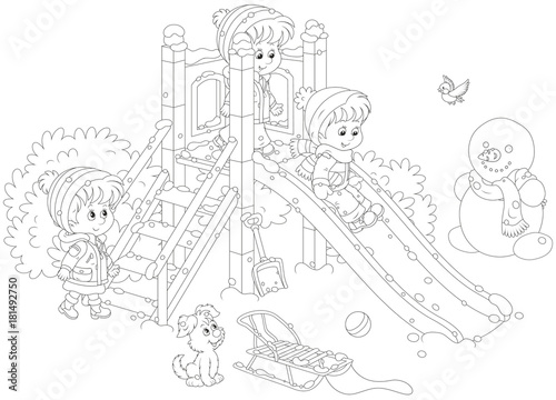 Little children playing on a slide at a playground in a winter park