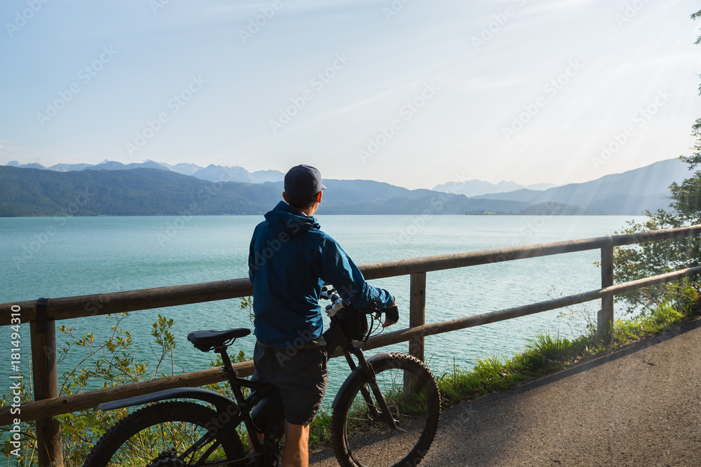 Fototapeta premium Man is riding his e-mountainbike around Walchensee with beautiful view towards Zugspitze in Germany