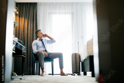 Mature businessman with smartphone in a hotel room. © Halfpoint