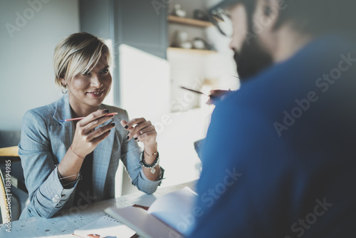 Coworkers working process at home.Young blonde woman working together with bearded colleague man at modern home office.People making conversation together.Blurred background.Horizontal. photo