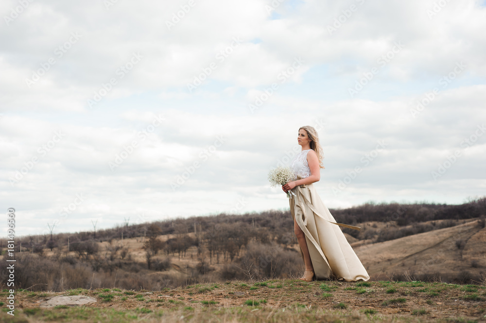 Portrait of a beautiful blonde with a bouquet of white flowers on the edge of a mountain Portrait of a beautiful blonde with a bouquet of white flowers on the edge of a mountain