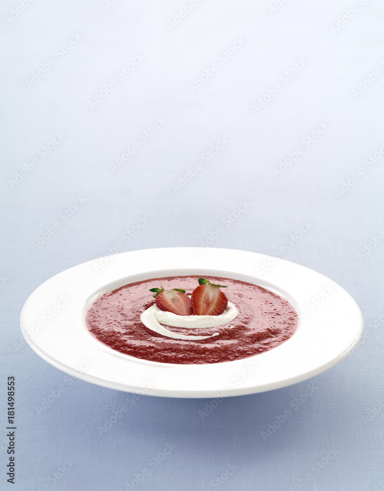 Fototapeta premium Delicious compot with red fruits and whipped cream in a plate