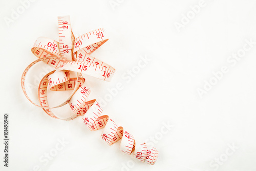 Curled measuring tape on a white background, top view with text space