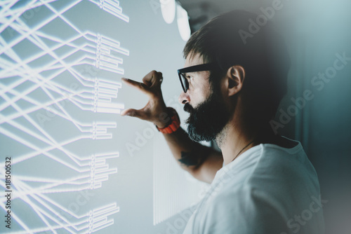 Concept of virtual panel display,diagram,digital graph interfaces.Attractive coworker touching virtual panel with graphs.Blurred background. Horizontal.