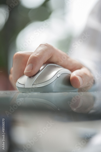 Close up of a man's hand using cordless mouse on glass table