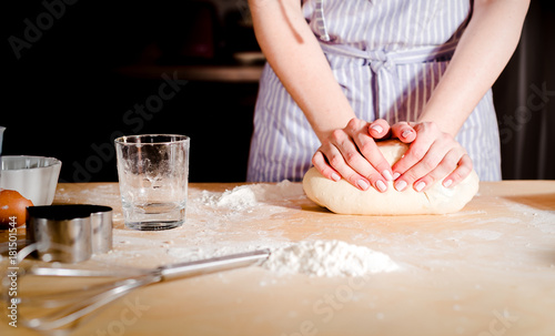 Woman's hands knead dough on a table