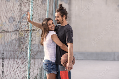 beautiful couple hanging out, flirting and relaxing while playing games on an asphalt basketball court