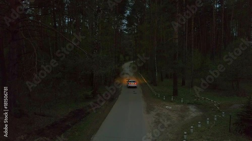 White Kia Rio car driving along the road in the autumn night forest. Rear view photo