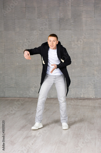 Young rapper on studio bakground. Teenager hip-hop dancer posing on grey studio background. Talented and skillful young street dancer.