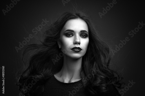 Portrait of the beautiful young woman with long brown hair posing at studio