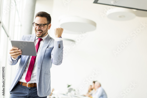 Happy businessman with tablet in office