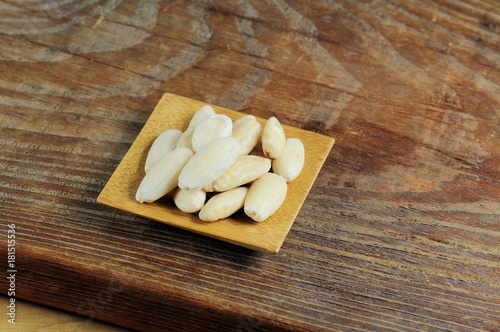 Blanched almonds on wooden background.