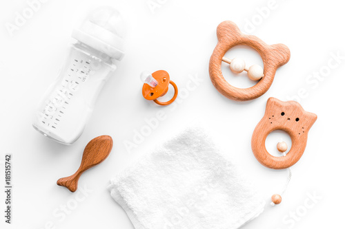 Baby accessories. Wooden toys, pacifier and bottle on white background top view