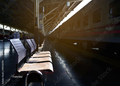 Empty old blue chairs at train station with soft lighting and black floor with a