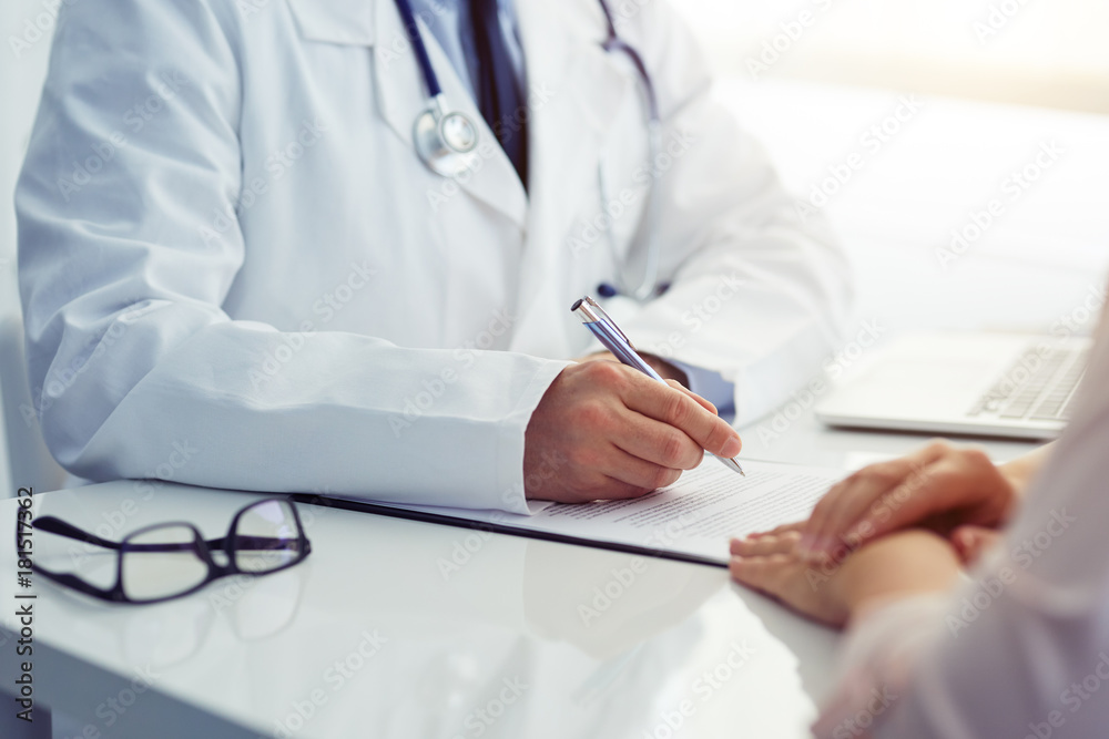 Doctor consults with his patient and writes notes on the clipboard Doctor consults with his patient and writes notes on the clipboard