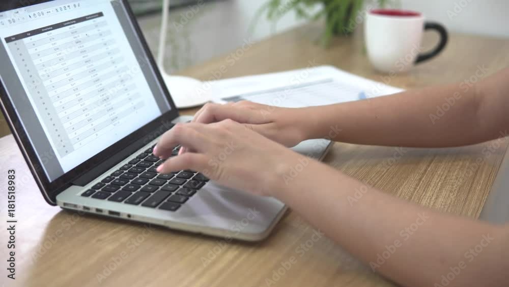 Young businesswoman using laptop at office workplace and checking the paper documents, surrounded by paper Young businesswoman using laptop at office workplace and checking the paper documents, surrounded by paper