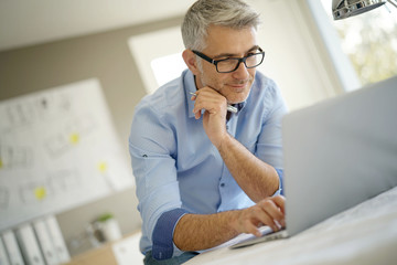 Architect in office working on construction project using laptop