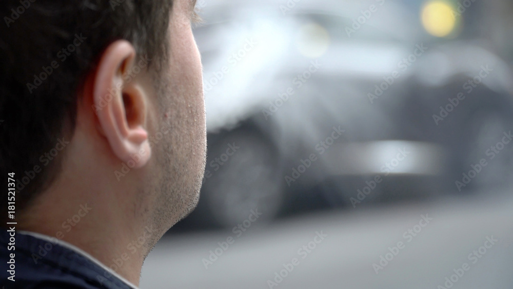 Over shoulder perspective view of young urban millennial hipster man smoking e-cig vape outside on city street. Exhale vaporized smoke created by flavored oil. Over shoulder perspective view of young urban millennial hipster man smoking e-cig vape outside on city street. Exhale vaporized smoke created by flavored oil.