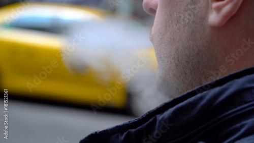 Canvas Print Young Millennial urban hipster blowing vapor electronic cigarette smoke outside on New York City street in day time
