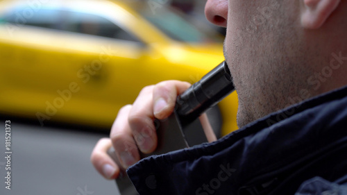 Photography Young hipster millennial man smoking vape e-cigarette outside on New York City street during day time