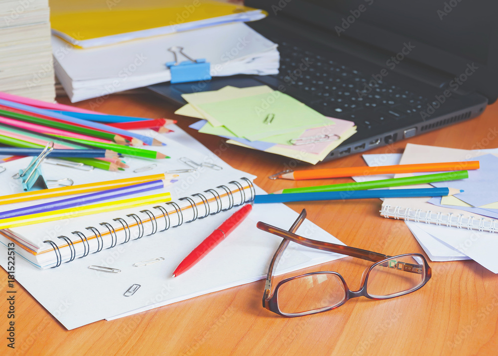 Glasses on the background of colored pencils and paper. The clutter on the desktop. Glasses on the background of colored pencils and paper. The clutter on the desktop.