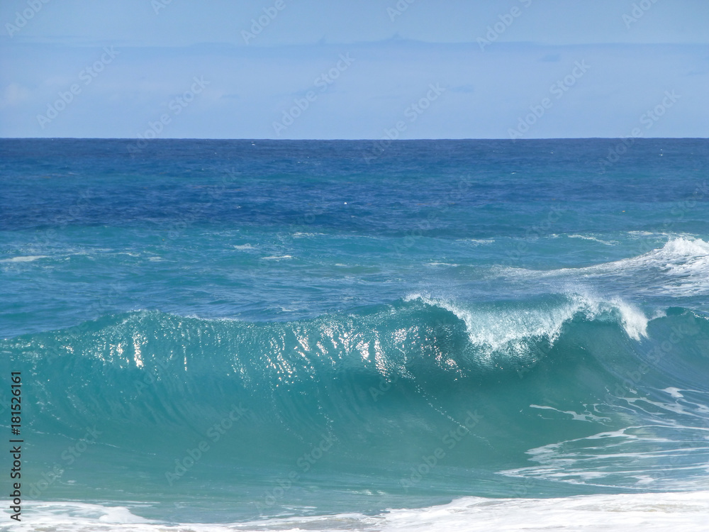 Naklejka premium Big turquoise wave that hits the beach.