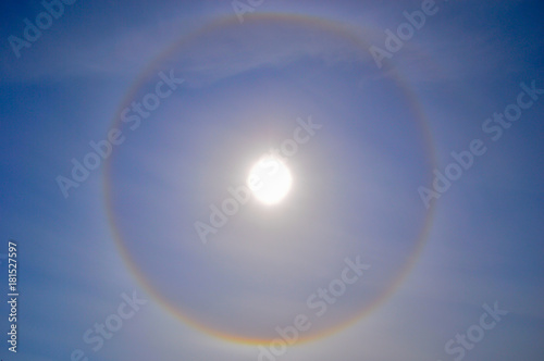 Fototapeta Naklejka Na Ścianę i Meble -  A halo around the sun in the middle of the day. Blue sky and foggy clouds.