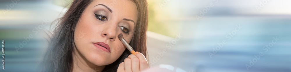 Young woman applying makeup on her face