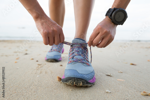 healthy lifestyle young fitness woman runner tying shoelace on beach