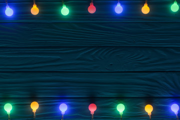 christmas garland lights on blue wooden background with copy space for your text. Top view