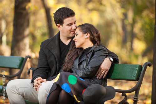 Happy couple sitting on a bench in autumn park © DC Studio