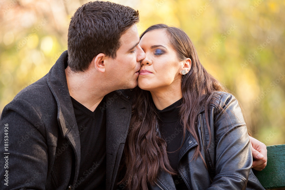 Fototapeta premium Close up of beautiful in love couple sitting on a bench in autumn park