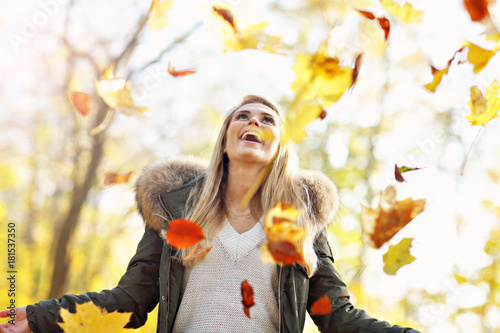 Happy woman playing with autumn leaves outdoors