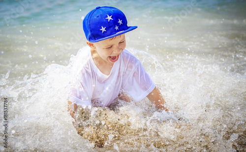 Fototapeta Naklejka Na Ścianę i Meble -  Happy caucasian boy is bathing in sea on summer vacation. Smiling child in sea water