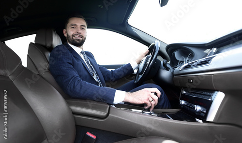 View from the side confident businessman sits at the wheel of a car © ASDF