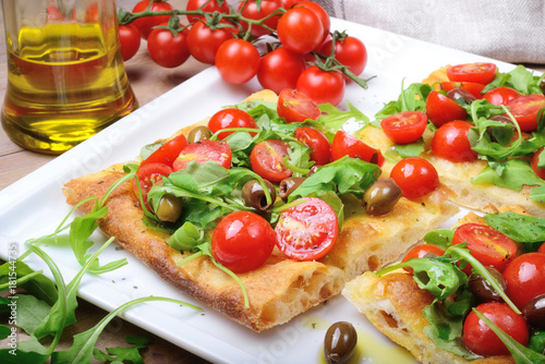 Focaccia with cherry tomatoes, arugula, olives and extra virgin olive oil