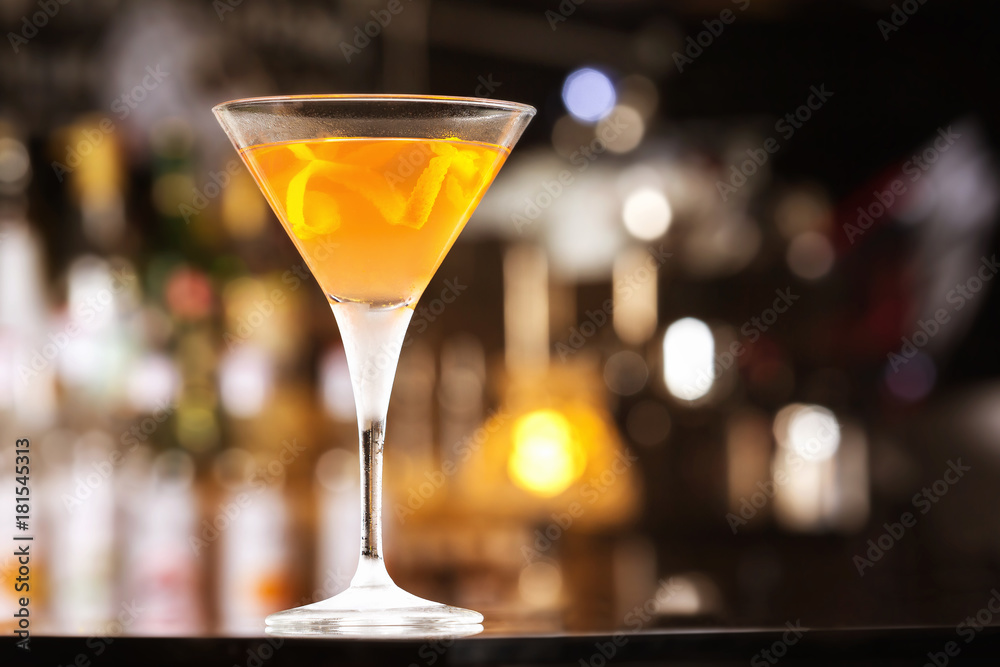 Fresh tall glass of tropical cocktail with rum and orange juice at bar counter background.