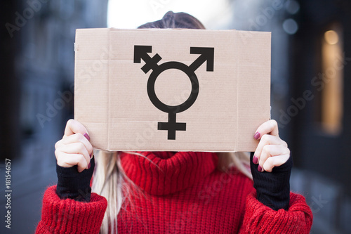 The symbol of the transgender in hands on a cardboard plate, covering (hiding) the face. photo